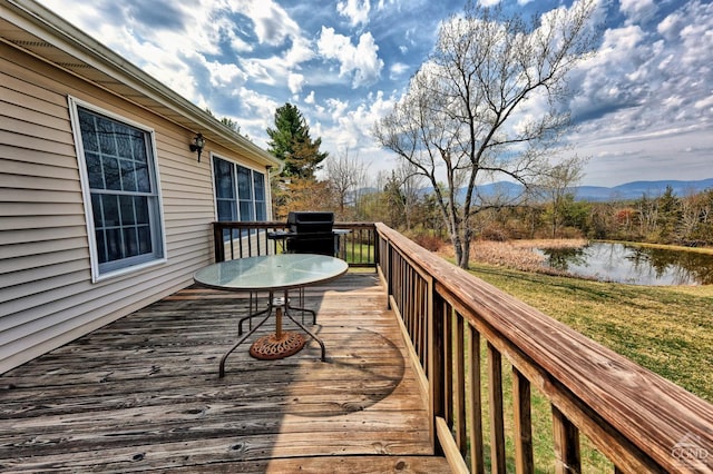 wooden terrace featuring a lawn, a water view, and a grill