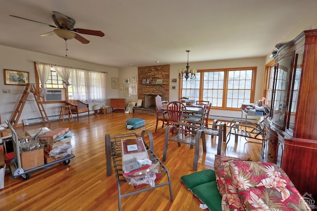 living area with plenty of natural light, ceiling fan with notable chandelier, baseboard heating, and a fireplace