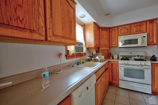 kitchen featuring brown cabinets, a sink, white appliances, light countertops, and light tile patterned floors