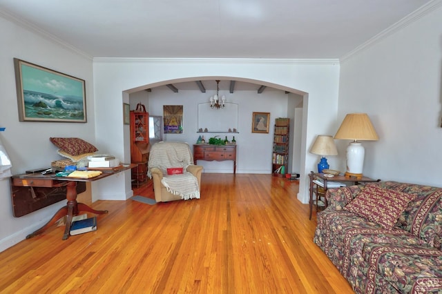 living room featuring arched walkways, baseboards, ornamental molding, and light wood-type flooring