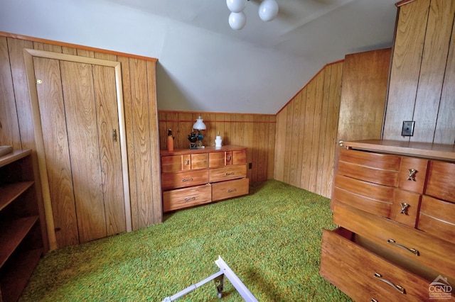 bedroom featuring wooden walls, vaulted ceiling, and carpet floors