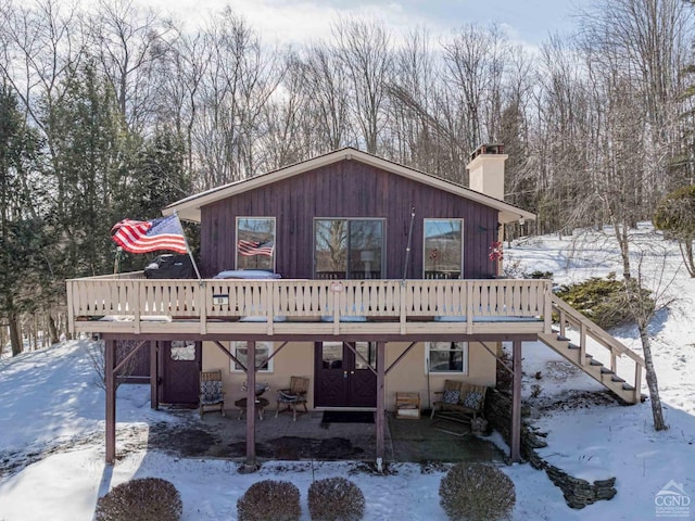 exterior space with stairway, a chimney, a deck, and stucco siding