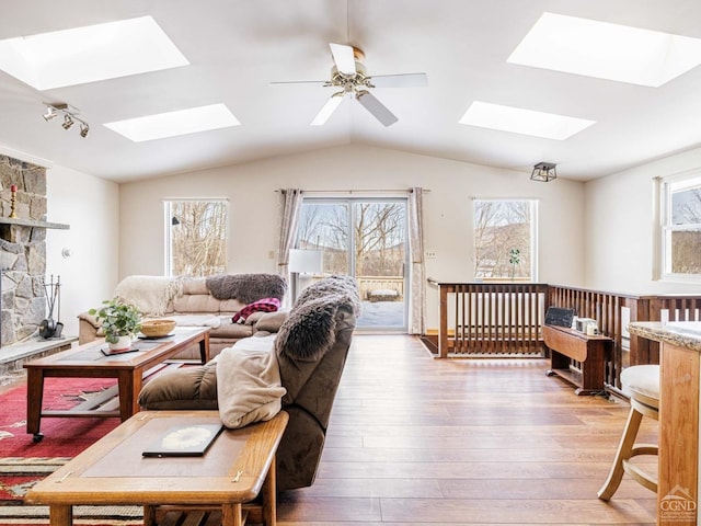 living room featuring vaulted ceiling, ceiling fan, wood finished floors, and a healthy amount of sunlight