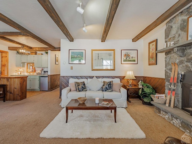 living area with light carpet, beamed ceiling, wooden walls, and a wainscoted wall