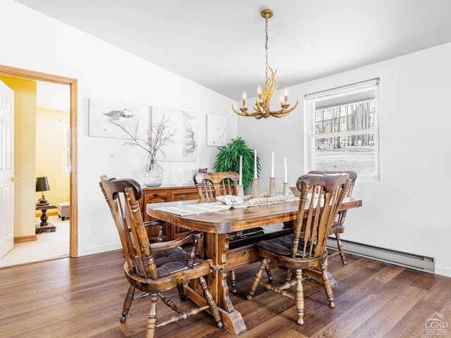 dining space featuring a baseboard radiator, a notable chandelier, wood finished floors, baseboards, and vaulted ceiling