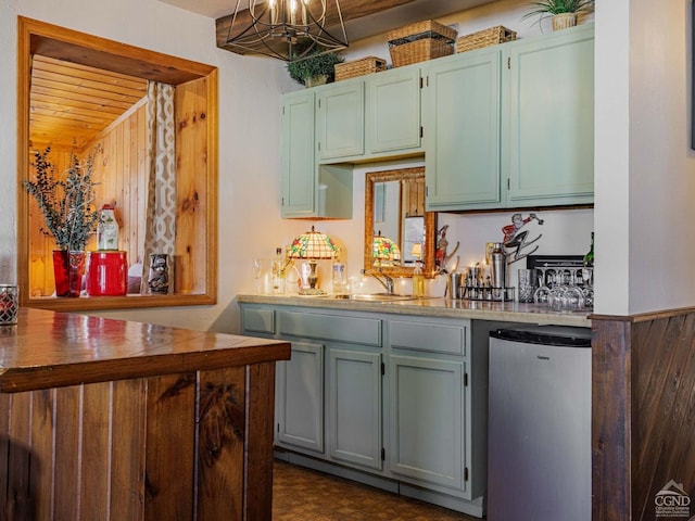 kitchen with freestanding refrigerator, hanging light fixtures, an inviting chandelier, light countertops, and a sink