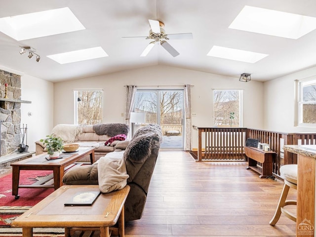 living area featuring light wood-style floors, plenty of natural light, and lofted ceiling with skylight