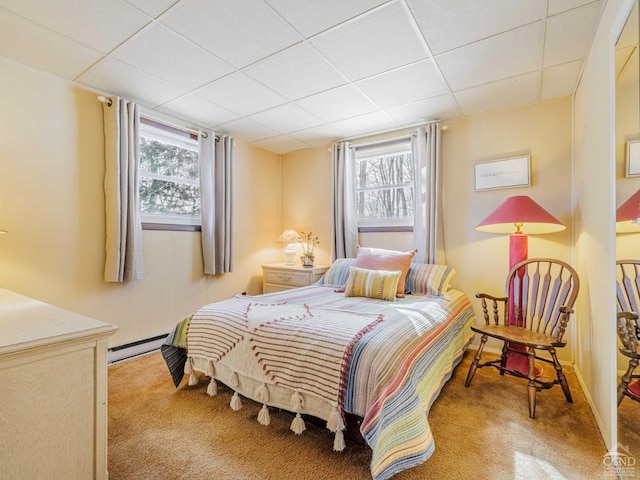 carpeted bedroom featuring a baseboard heating unit and a paneled ceiling