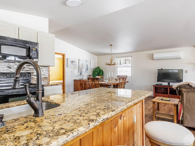 kitchen with black microwave, light stone counters, white cabinetry, open floor plan, and a wall mounted AC