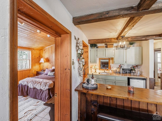 kitchen with light tile patterned flooring, wooden counters, beam ceiling, dishwasher, and pendant lighting