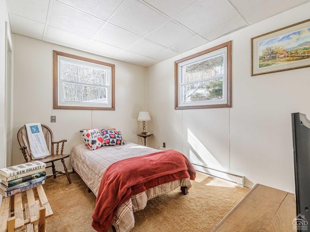 bedroom with a baseboard heating unit, multiple windows, and carpet flooring