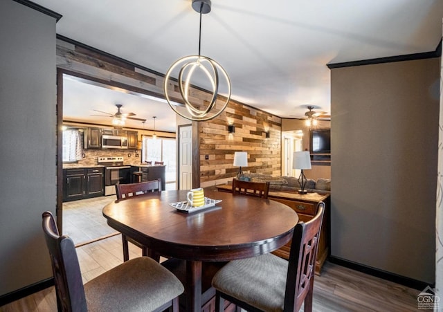 dining room with light hardwood / wood-style floors, ceiling fan, ornamental molding, and wood walls