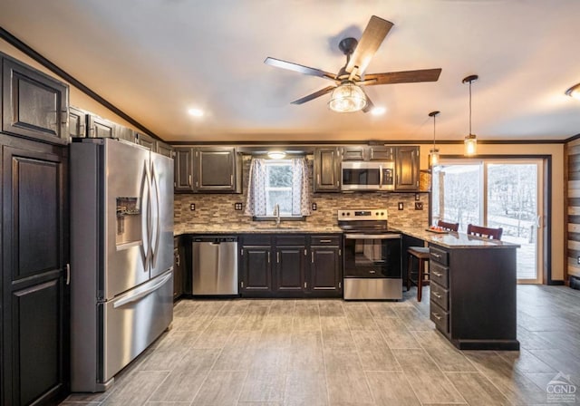 kitchen with sink, ceiling fan, light stone countertops, appliances with stainless steel finishes, and decorative light fixtures