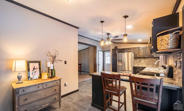 kitchen with ceiling fan, light stone countertops, stainless steel refrigerator with ice dispenser, decorative backsplash, and ornamental molding