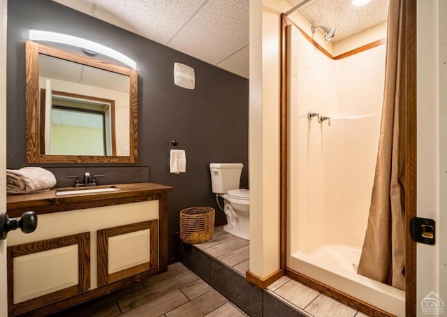 bathroom featuring a shower with curtain, a drop ceiling, vanity, and toilet