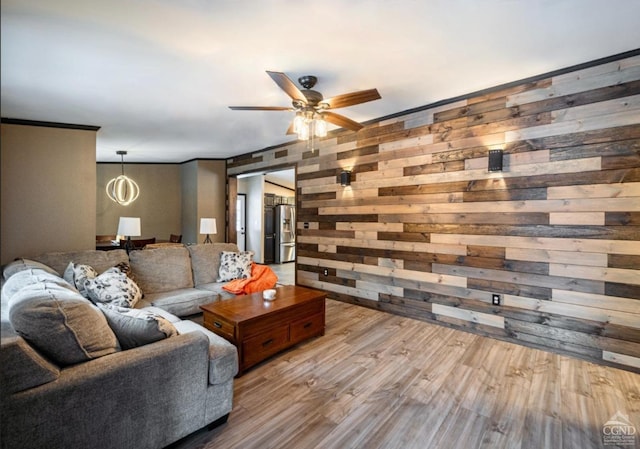 living room featuring light hardwood / wood-style flooring, ceiling fan, wooden walls, and crown molding