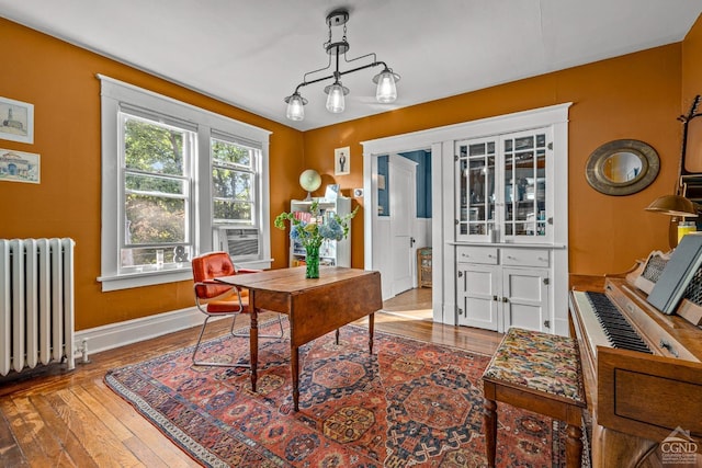 home office featuring hardwood / wood-style flooring, cooling unit, and radiator