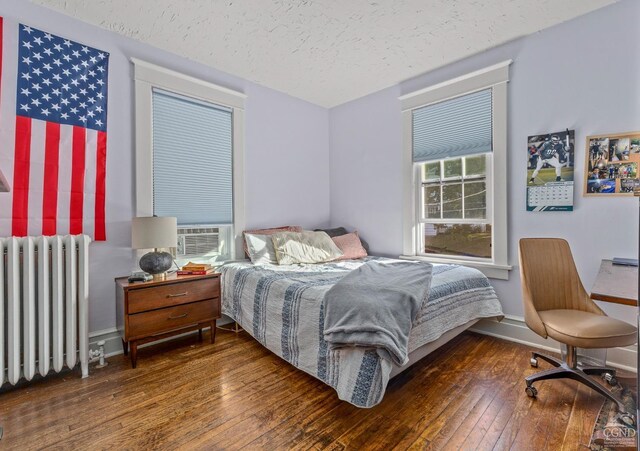 bedroom featuring a textured ceiling, radiator, and dark wood-type flooring