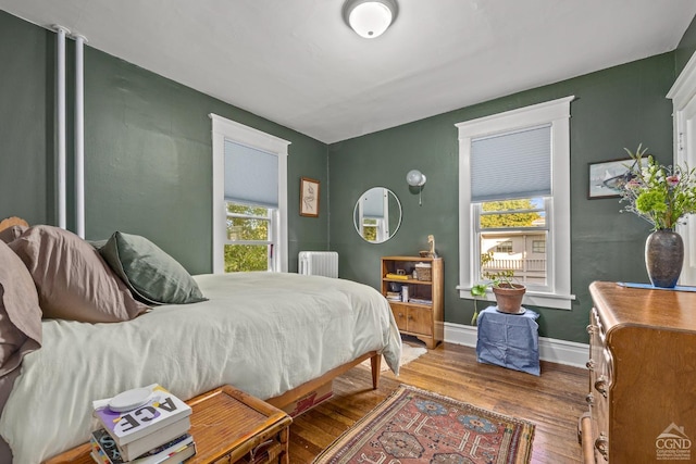 bedroom with radiator heating unit and wood-type flooring