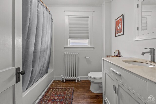 full bathroom featuring vanity, hardwood / wood-style flooring, toilet, ornamental molding, and radiator heating unit