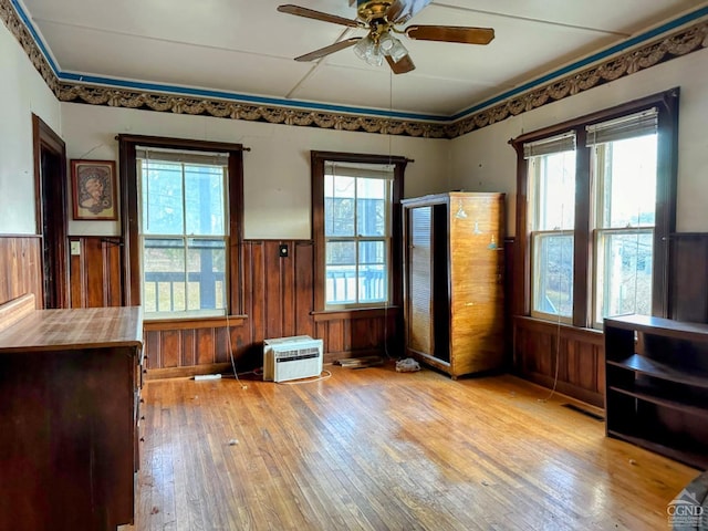 interior space with a wealth of natural light, wooden walls, and light hardwood / wood-style floors