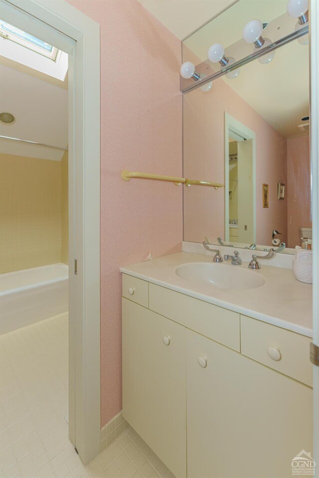 bathroom featuring tile patterned flooring, vanity, and a skylight