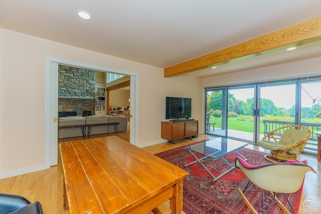 living room featuring beam ceiling, a fireplace, and wood-type flooring