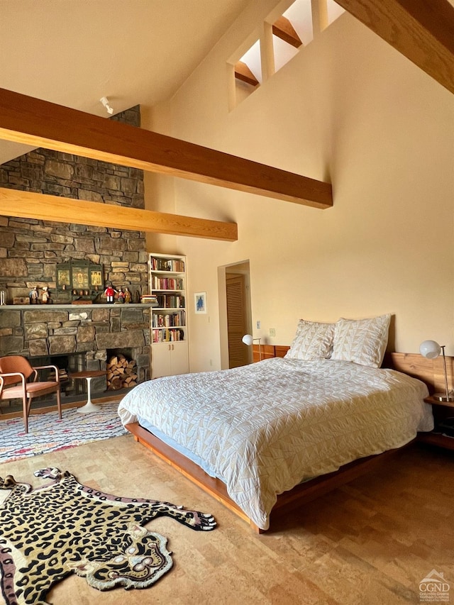 bedroom with carpet flooring, beam ceiling, a stone fireplace, and high vaulted ceiling