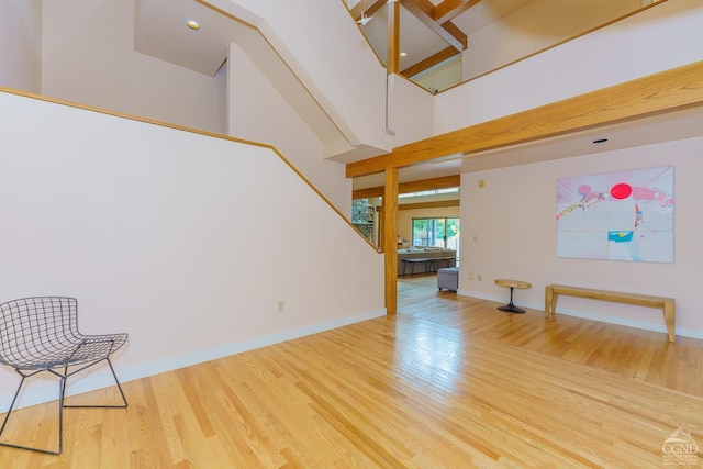 unfurnished room with a towering ceiling and hardwood / wood-style flooring