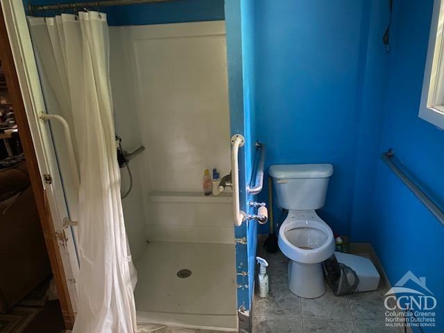 bathroom with tile patterned flooring, curtained shower, and toilet