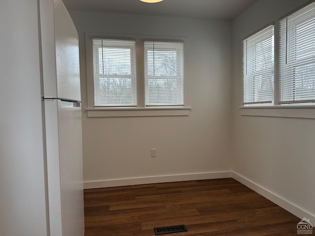 empty room with visible vents, baseboards, and dark wood-style flooring