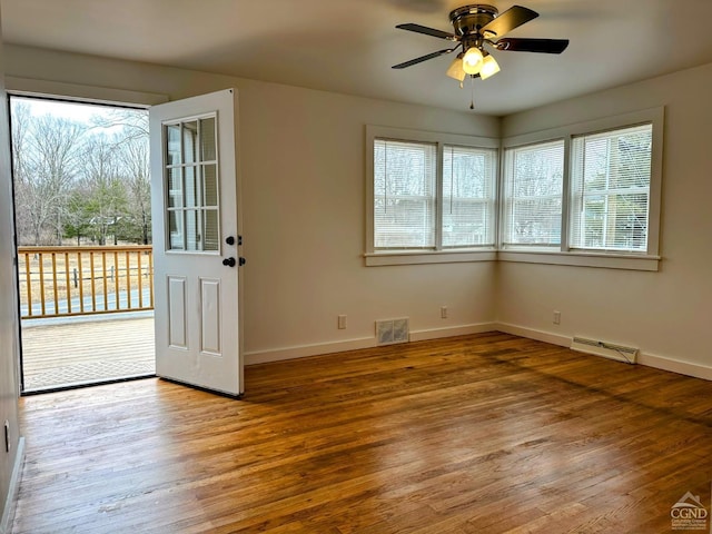 unfurnished room with a wealth of natural light, visible vents, baseboards, and wood finished floors