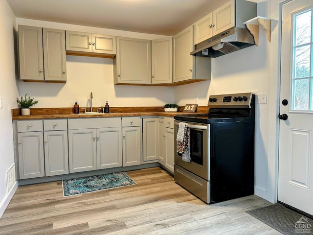 kitchen featuring electric range, gray cabinets, under cabinet range hood, a sink, and light wood finished floors