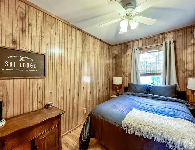 bedroom with ceiling fan, wood walls, light wood-type flooring, and crown molding