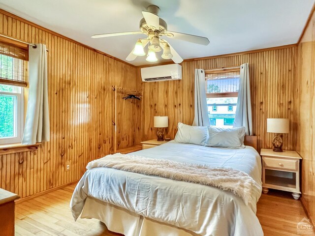 bedroom featuring a wall mounted air conditioner, ceiling fan, hardwood / wood-style flooring, and multiple windows