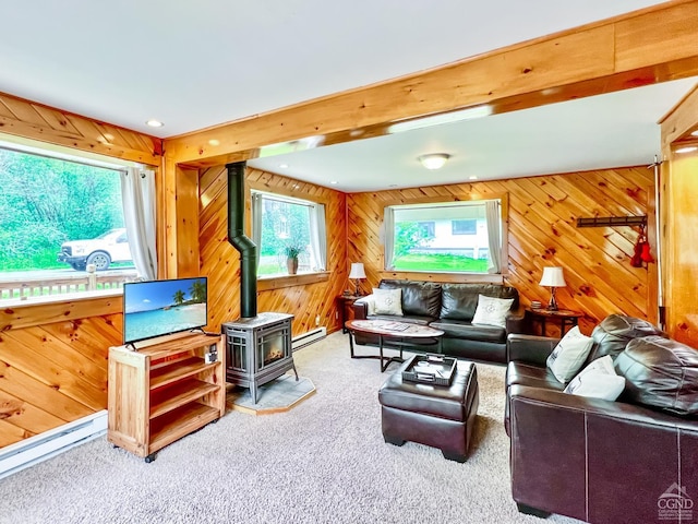 living room with carpet flooring, wood walls, a wood stove, and a baseboard heating unit