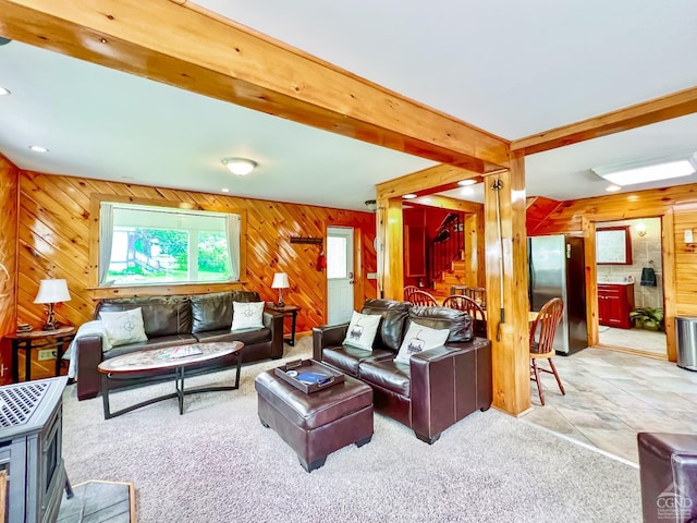 living room with beam ceiling, wood walls, and light colored carpet