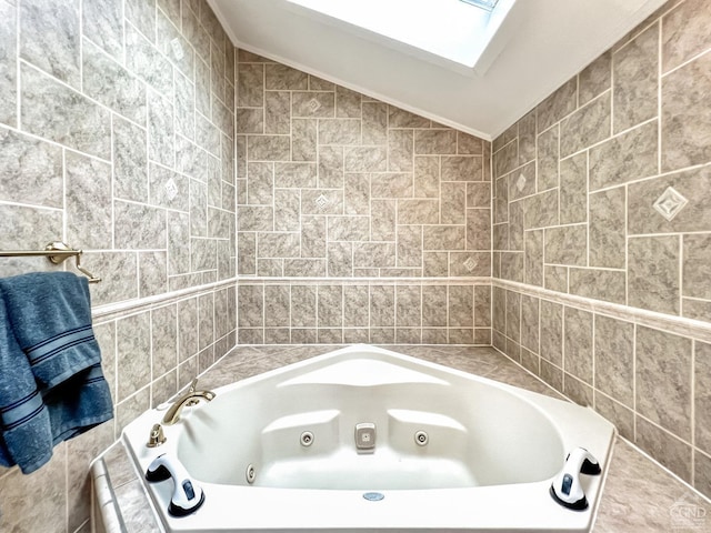 bathroom with vaulted ceiling with skylight, a washtub, and tile walls