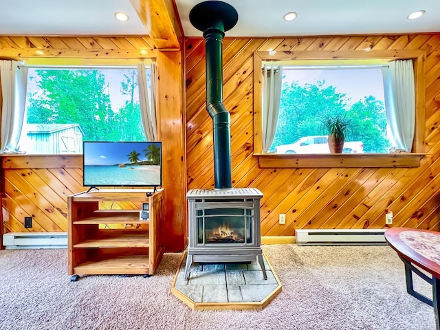 carpeted living room featuring a wood stove, a wealth of natural light, and wood walls