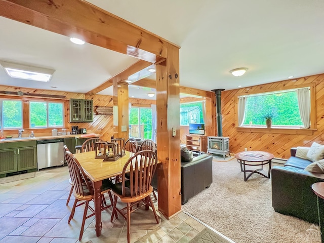 dining area featuring a wood stove, wooden walls, and sink