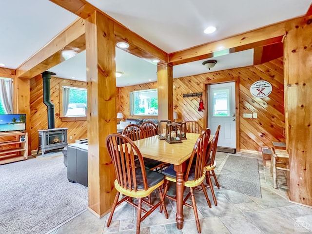 dining room featuring a wood stove, a wealth of natural light, and wooden walls