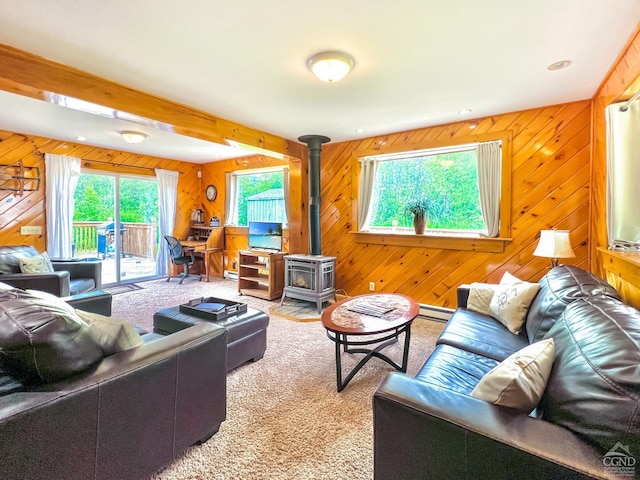 carpeted living room with wood walls, a wood stove, and a baseboard radiator