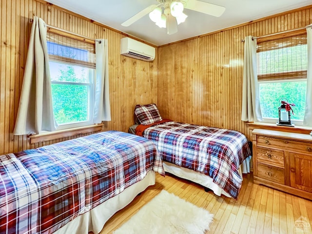 bedroom with hardwood / wood-style flooring, a wall unit AC, ceiling fan, and wooden walls