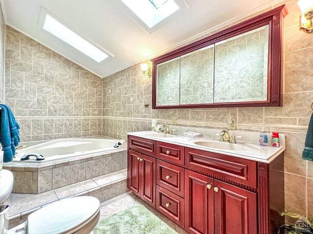 bathroom with vanity, vaulted ceiling with skylight, a relaxing tiled tub, toilet, and tile walls