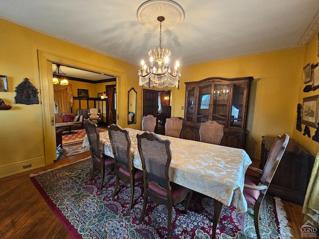 dining space with crown molding, dark hardwood / wood-style floors, and an inviting chandelier