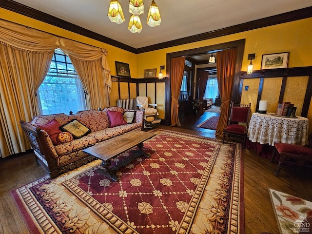 living room featuring ornamental molding, hardwood / wood-style flooring, a healthy amount of sunlight, and a notable chandelier