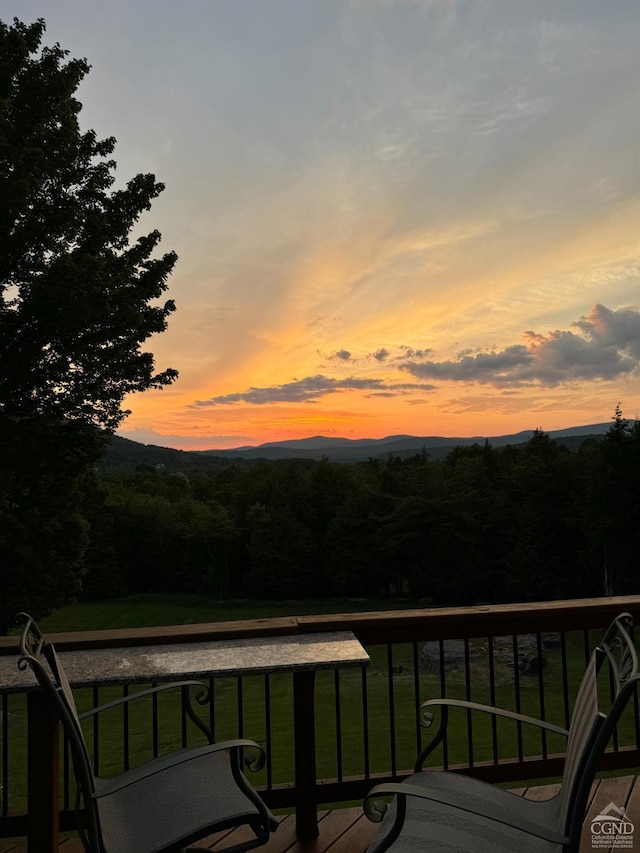 deck at dusk featuring a lawn