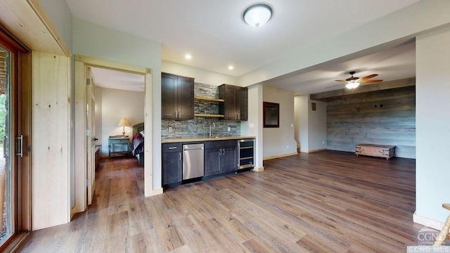 kitchen featuring beverage cooler, backsplash, wood walls, light hardwood / wood-style floors, and dark brown cabinets