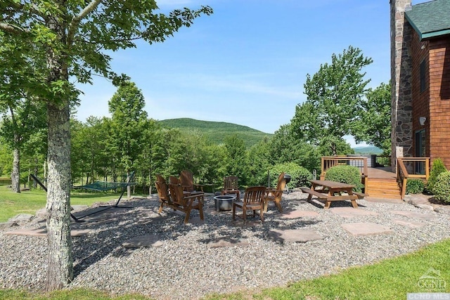 view of yard with a patio area, a deck with mountain view, and a fire pit