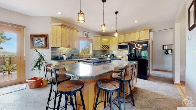 kitchen with black refrigerator, light brown cabinets, a center island, and tasteful backsplash